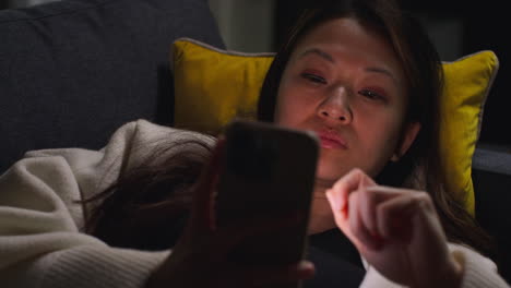 Close-Up-Of-Woman-Spending-Evening-At-Home-Lying-On-Sofa-With-Mobile-Phone-Scrolling-Through-Internet-Or-Social-Media-5